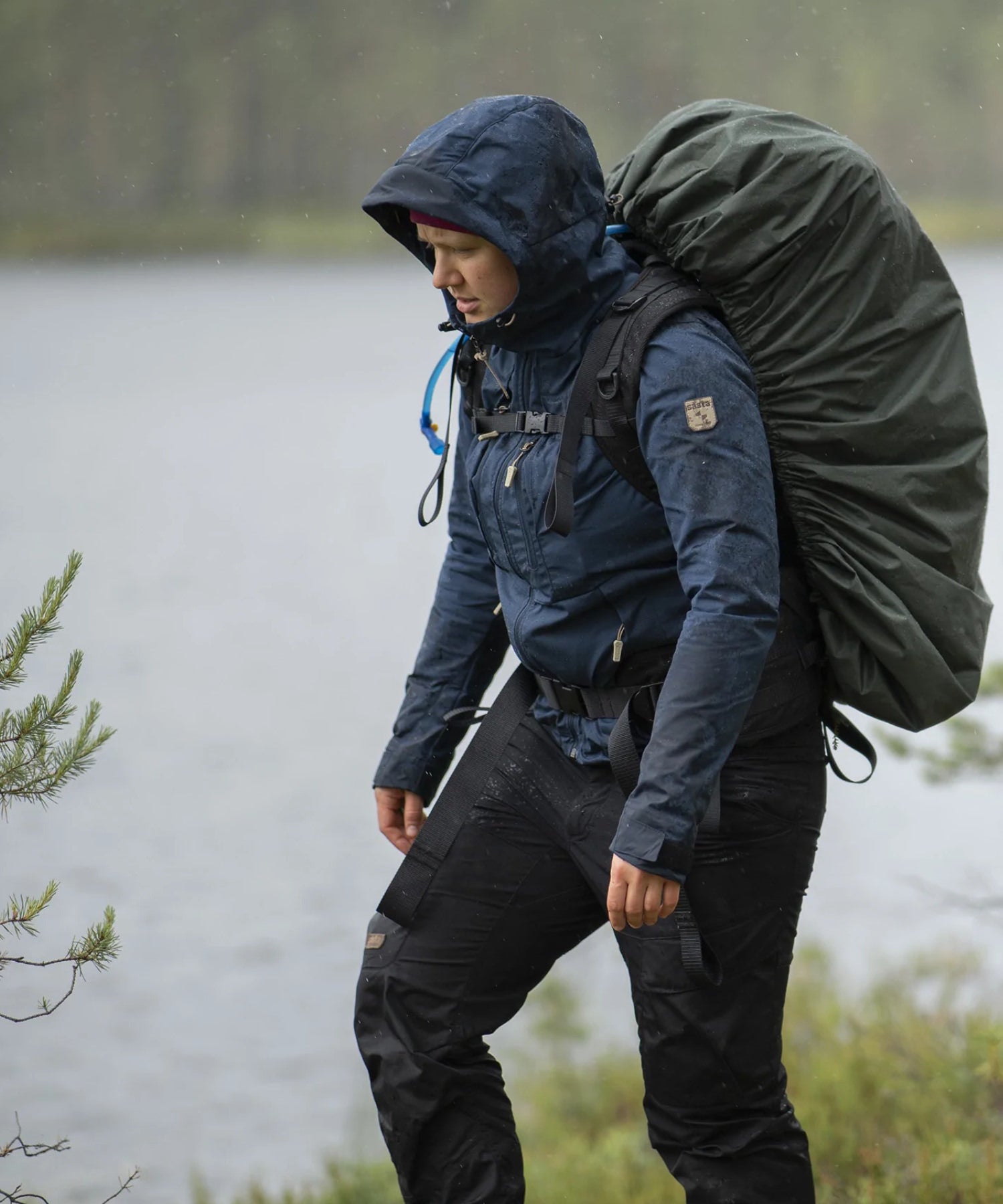 Uomo fa escursione durante un temporale con il suo zaino savotta a la cover antipioggia