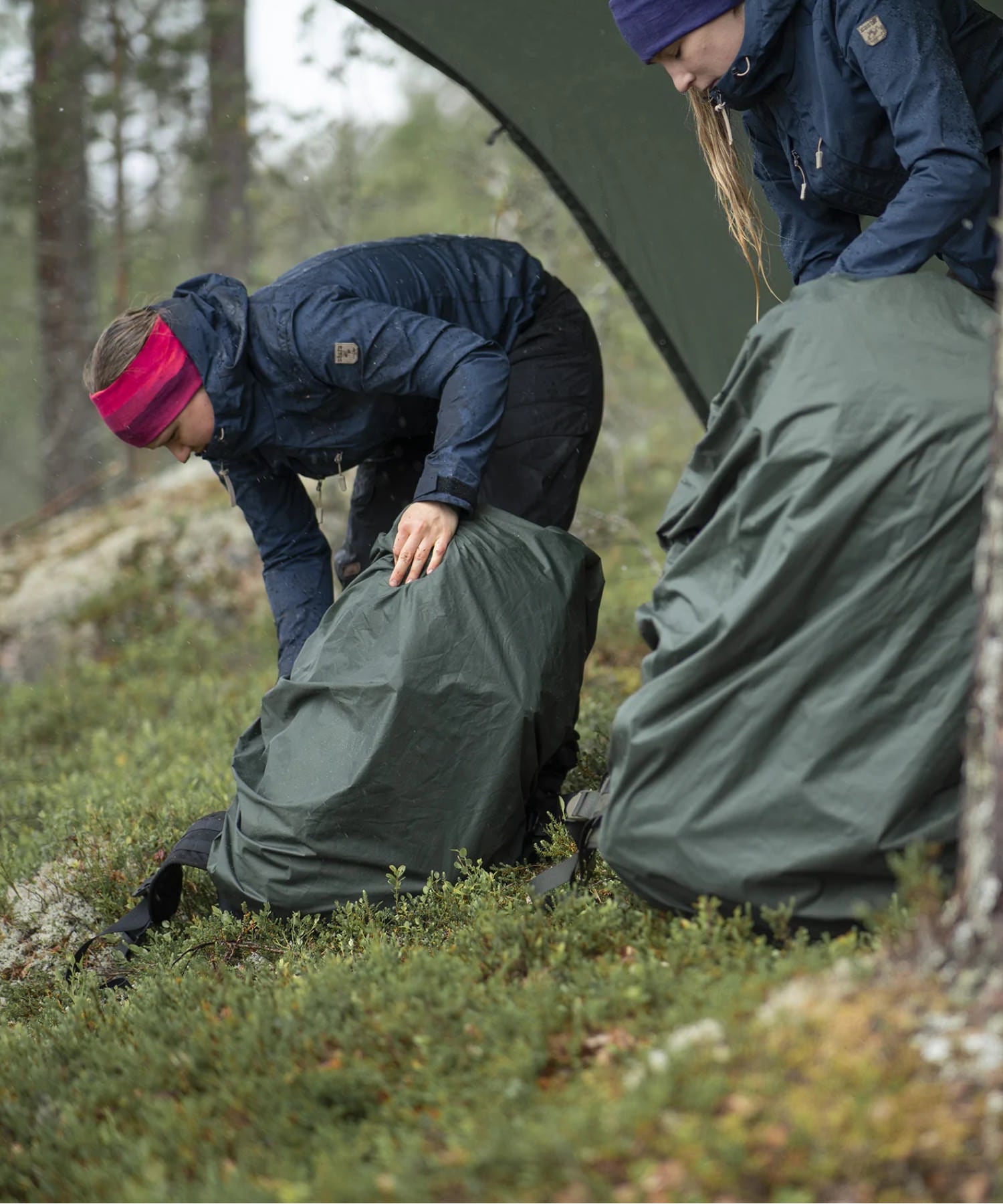 due donne si fermano a mettere la cover antipioggia sugli zaini savotta