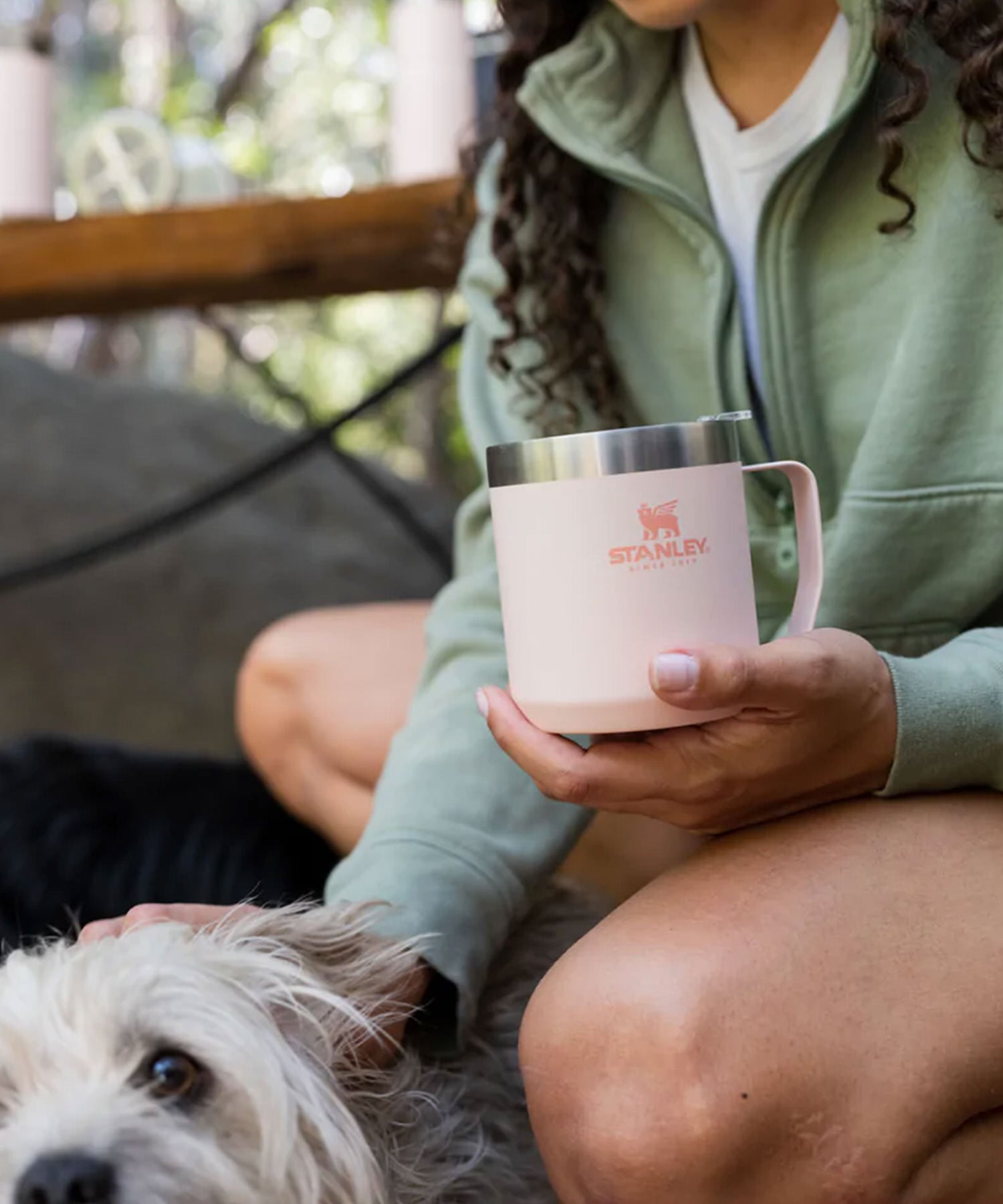 Donna a passeggio col cane si ferma a bere un caffè con la sua Camp Mug di Stanley