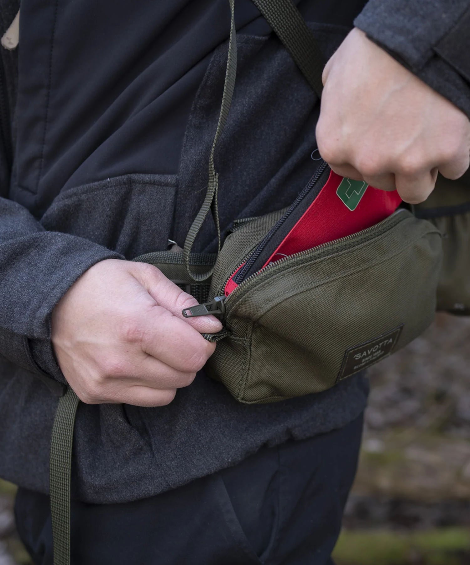 donna prende il borsellino dalla tasca orizzontale montata sullo zaino savotta
