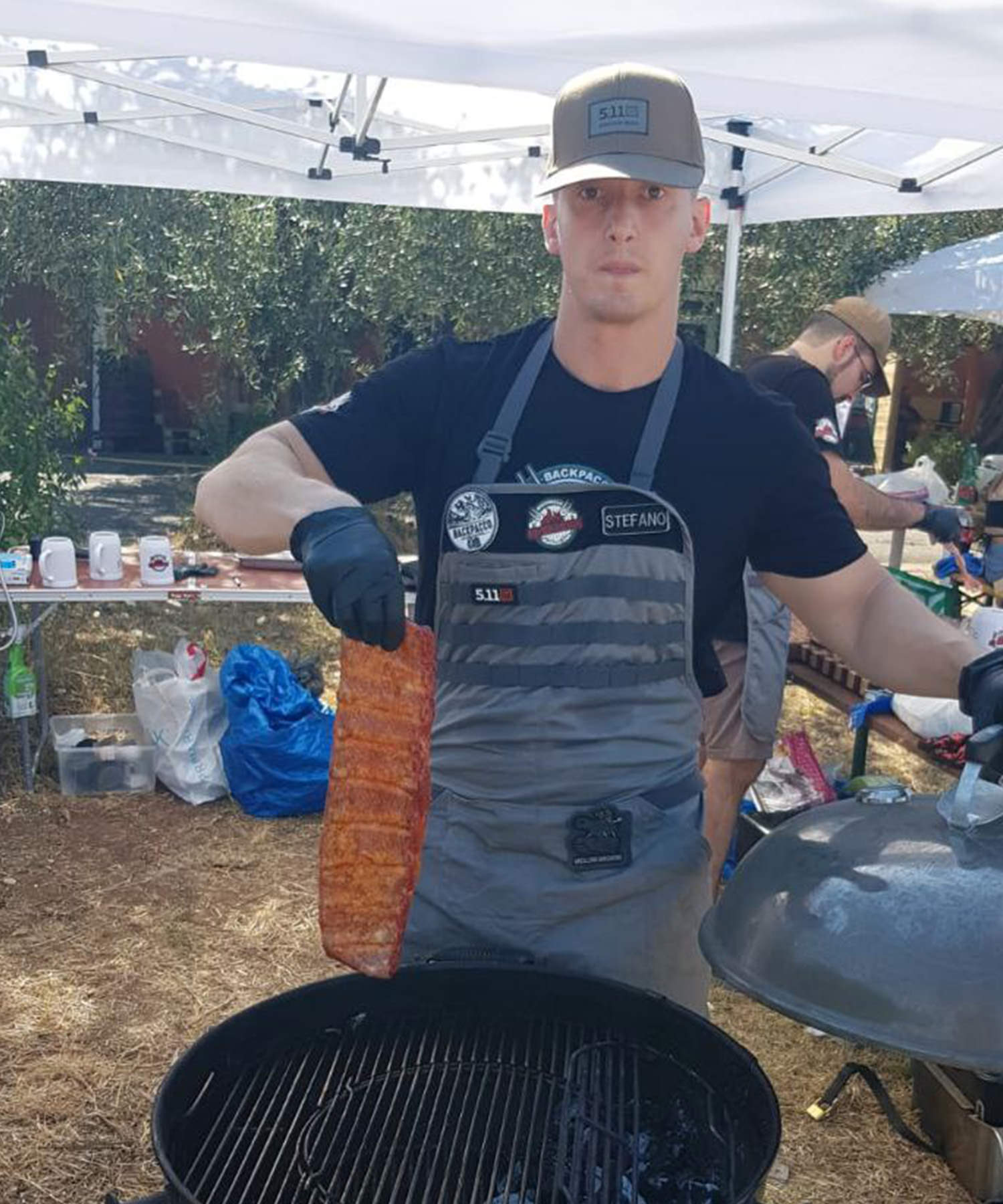 Stefano dei rubbaribs posiziona la carne sulla griglia indossando un apron 5.11