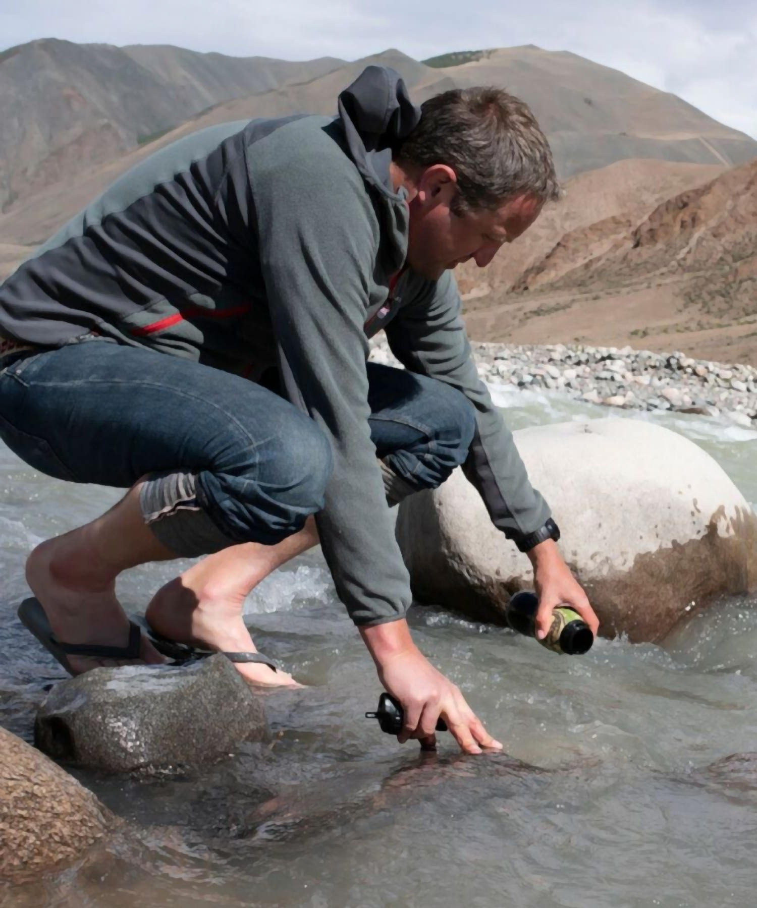 uomo raccoglie acqua con borraccia water to go dal fiume