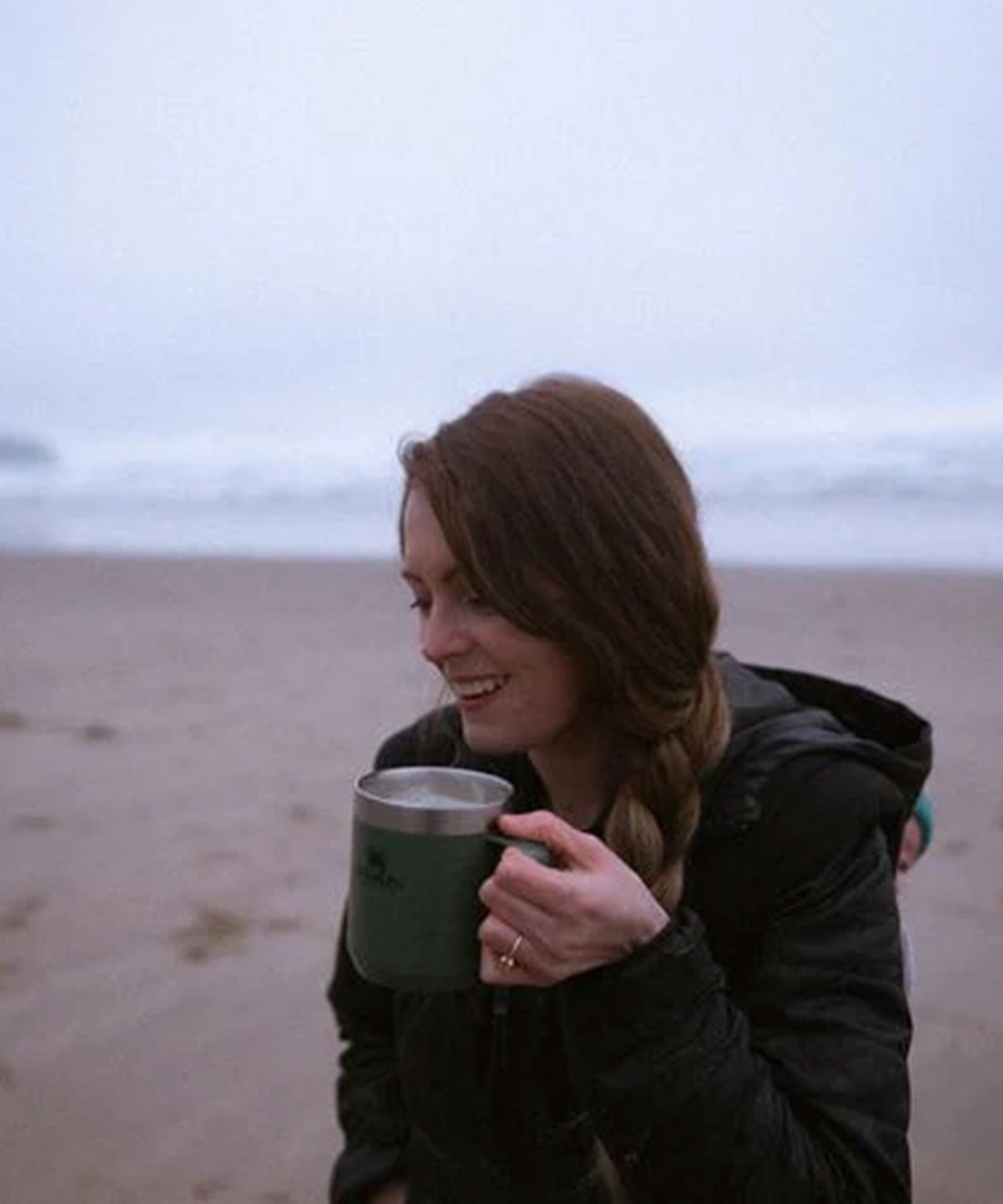 ragazza beve un the caldo in riva al mare
