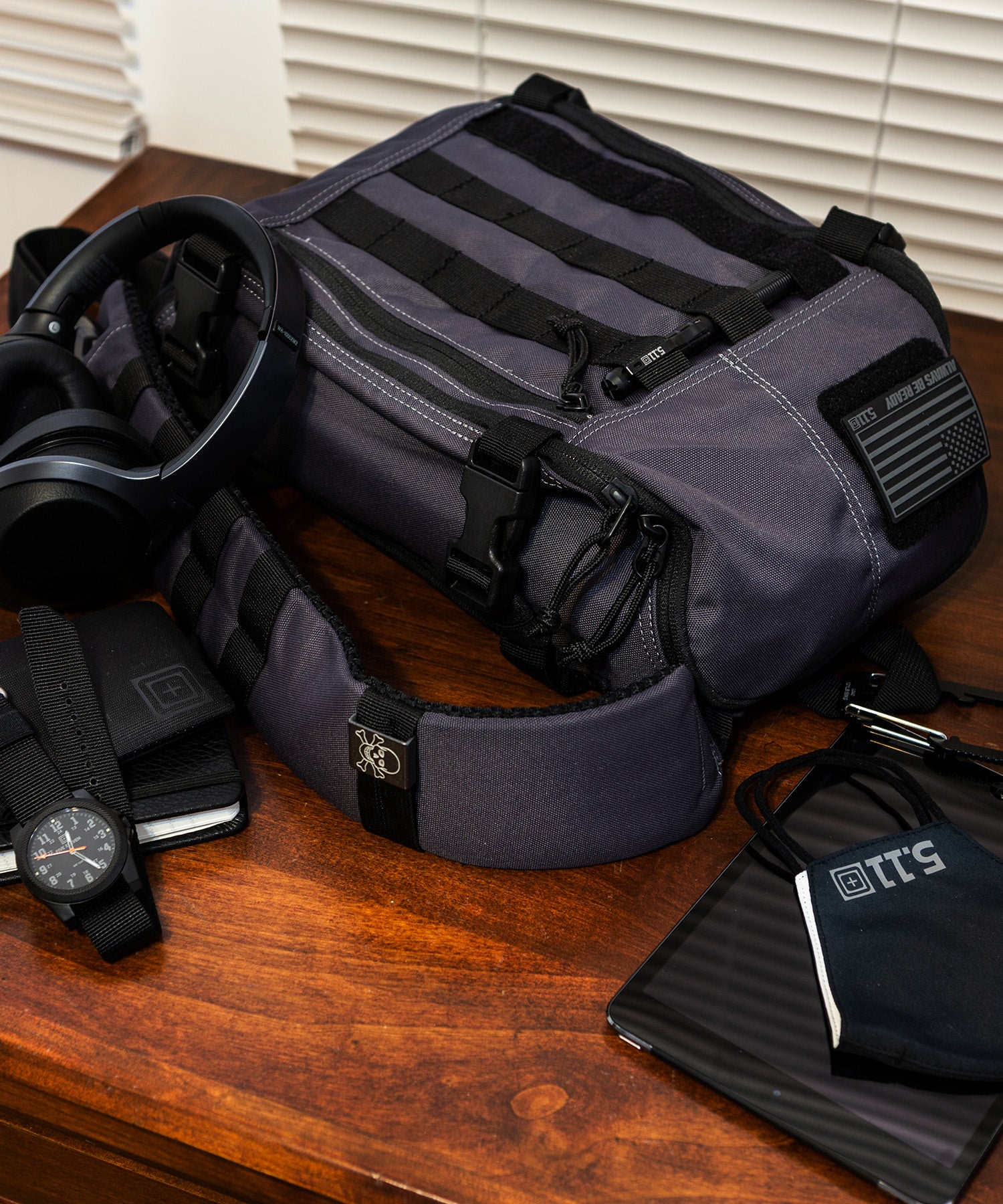 sling pack coal con accessori sul tavolo
