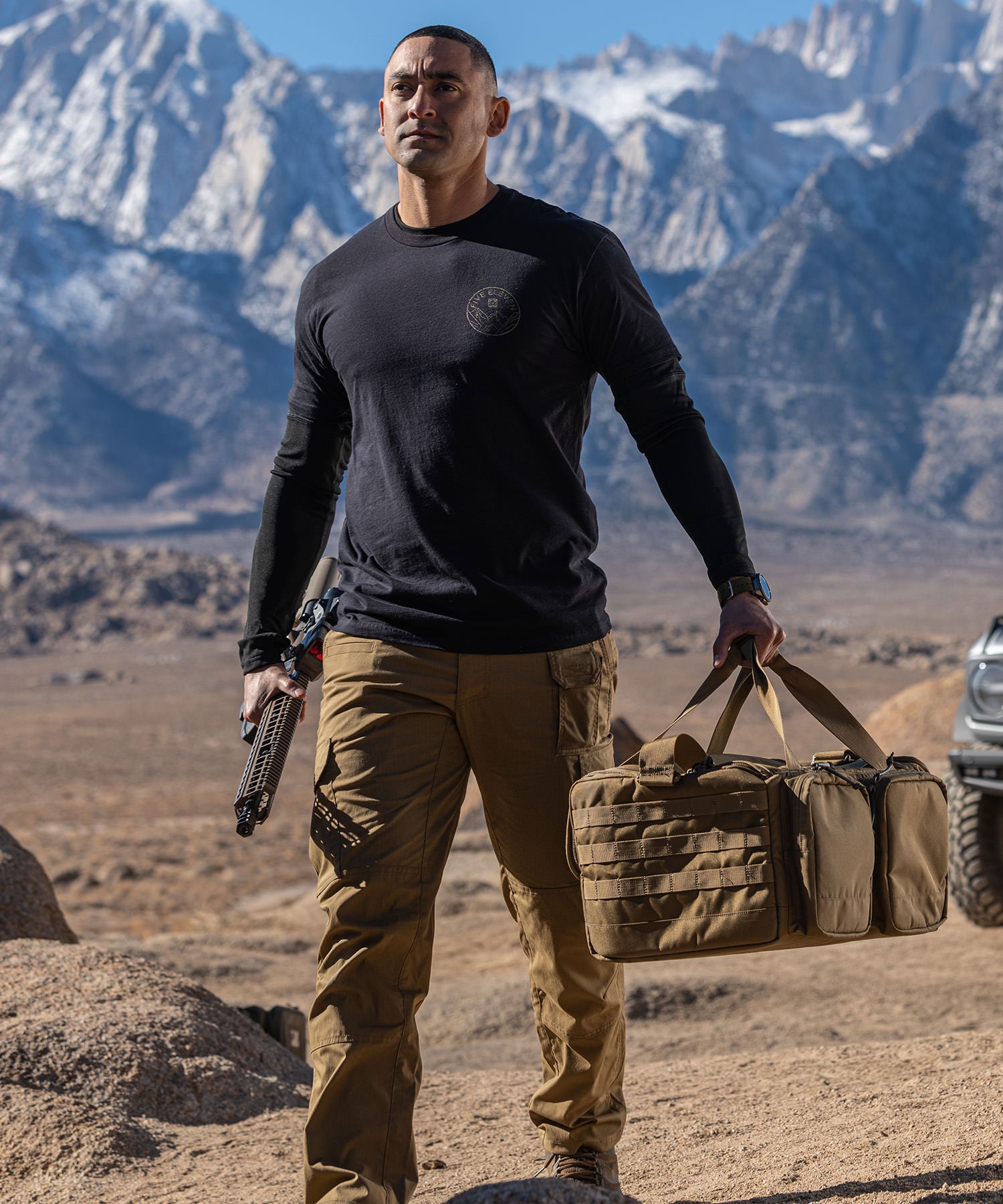 uomo lascia il fuoristrada nel deserto e si allontana con fucile e borsa range ready trainer bag di 5.11