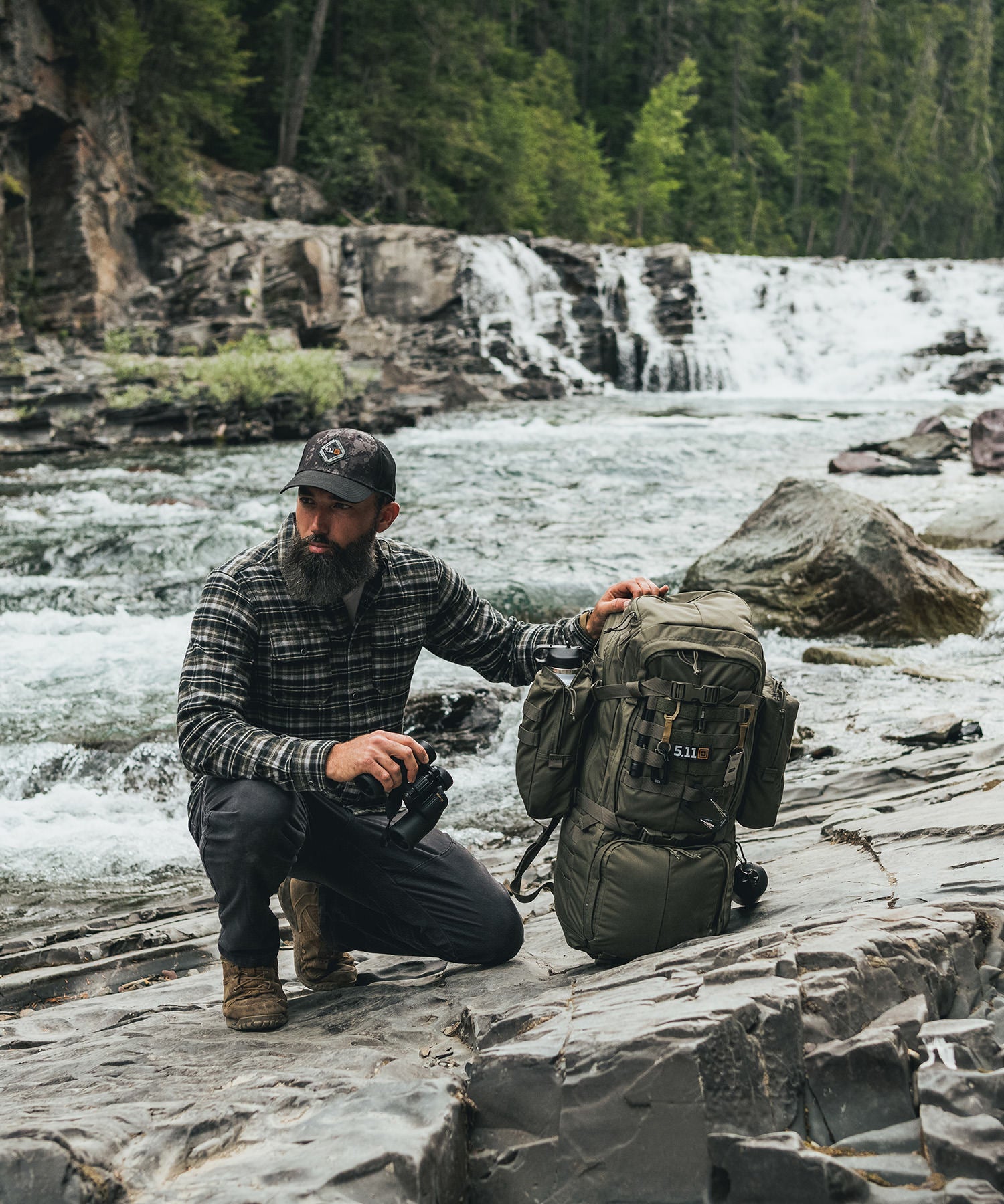 uomo sosta su un fiume con zaino e cappello 5.11