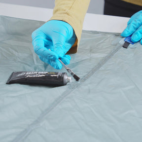 Gear Aid Seam Grip + SIL Silicone Sealant Sigillante per tende in silicone impermeabilizzante per cuciture e tessuti siliconati da 28 g o 42 in tubetto verticale per manutenzione attrezzatura outdoor su sfondo bianco.