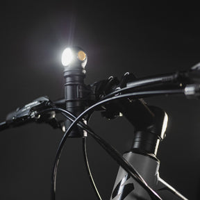 Armytek Bicycle Mount ABM-01. Supporto per bicicletta progettato per il fissaggio sicuro di torce con diametro del corpo di 24.5 mm. Costruito in materiale plastico robusto, presenta un morsetto da manubrio con interno dentellato e manopola di serraggio a vite per garantire massima stabilità. Il sistema di ritenzione superiore blocca la torcia in posizione tramite un anello elastico resistente, rendendolo ideale per l'illuminazione durante le uscite in bici.