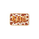 Patch ricamata in pelle 5.11 Tactical Country And Camo, sfondo con fantasia a macchie di mucca (cow print) marrone e beige, scritta 5.11 e testo Country And Camo in arancione, patch rettangolare con bordo cucito a cordoncino