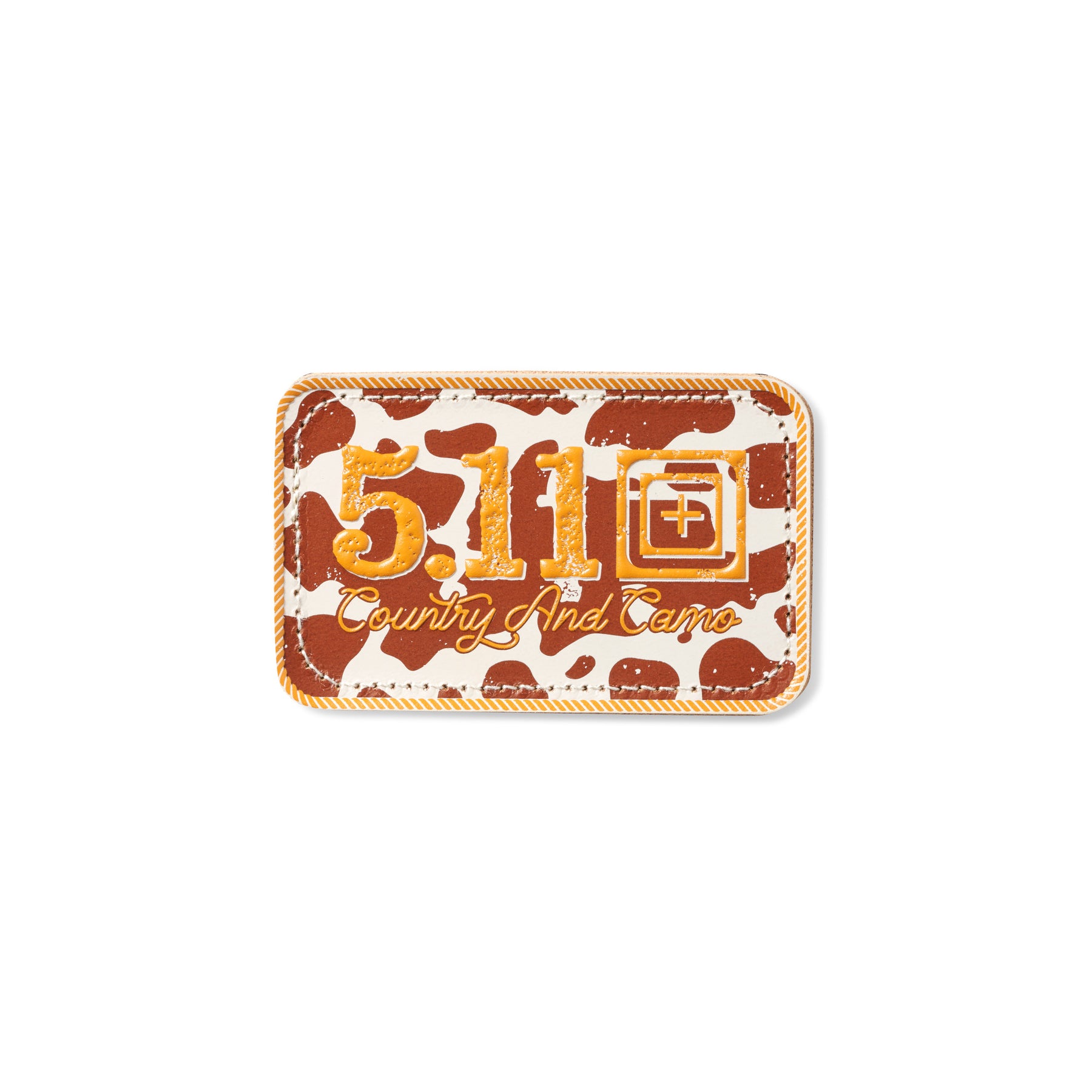 Patch ricamata in pelle 5.11 Tactical Country And Camo, sfondo con fantasia a macchie di mucca (cow print) marrone e beige, scritta 5.11 e testo Country And Camo in arancione, patch rettangolare con bordo cucito a cordoncino