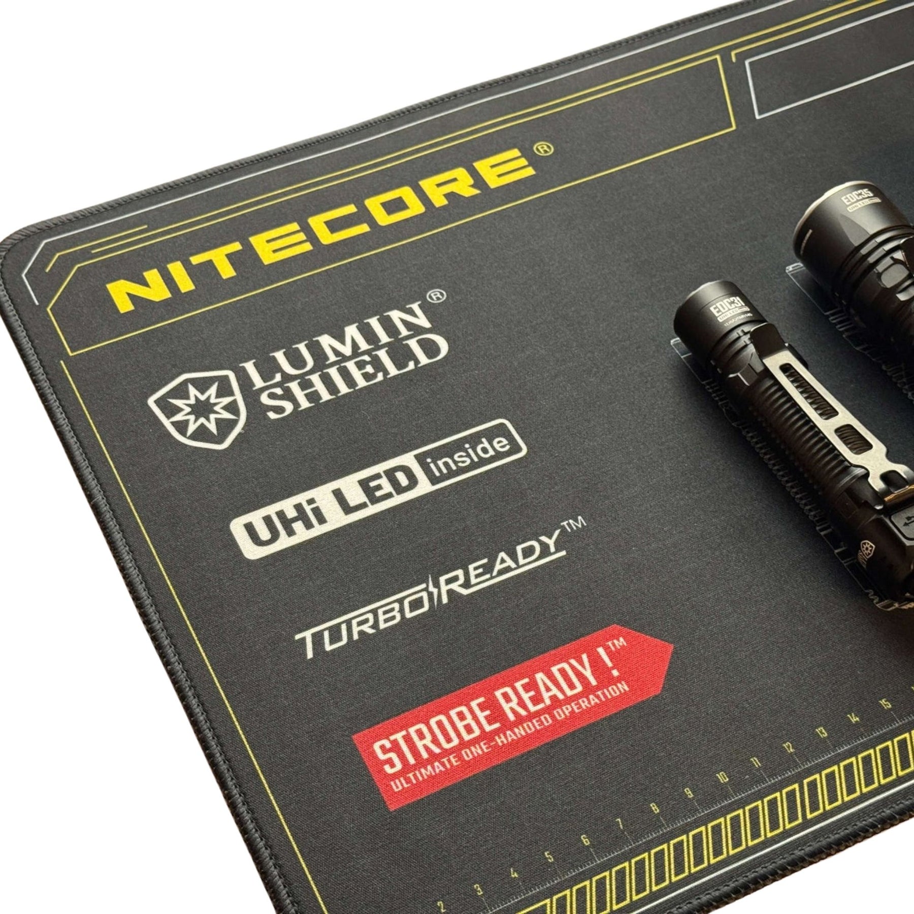 Nitecore Tappetino Mouse XL. Sottomano tecnico da scrivania con schemi grafici di torce serie EDC e righelli graduati sui bordi. Superficie ampia in tessuto morbido per manutenzione o gaming con loghi tecnologia Lumin Shield.