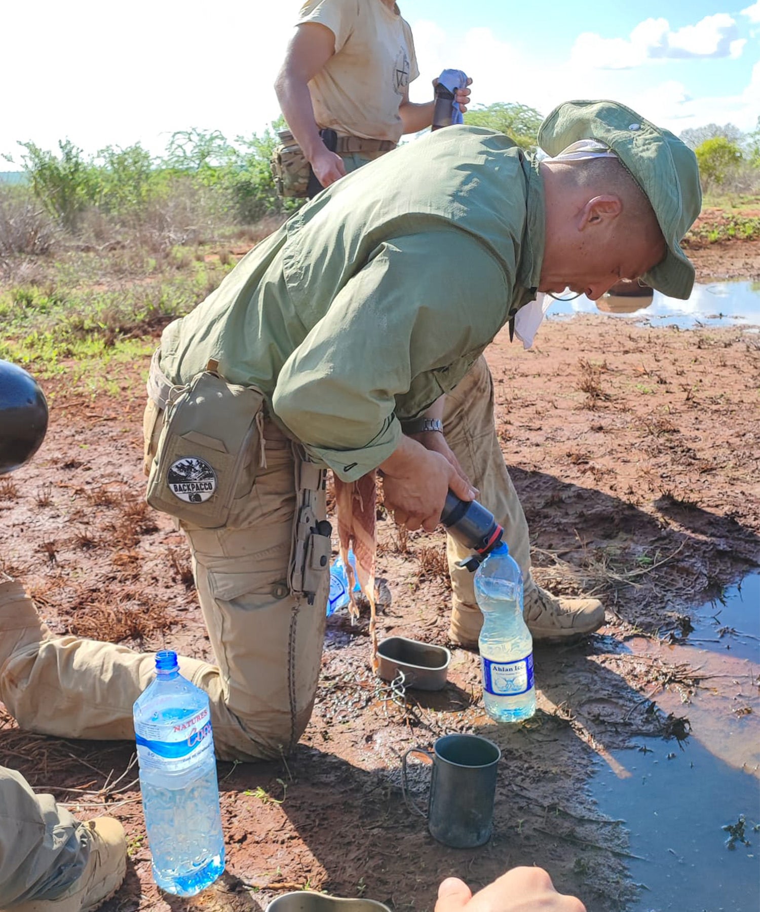 Milo filtra l'acqua di una pozzanghera con la water to go mentre ha alla cintura la sua UCR Ifak durante lo SNAKE 22 in kenya