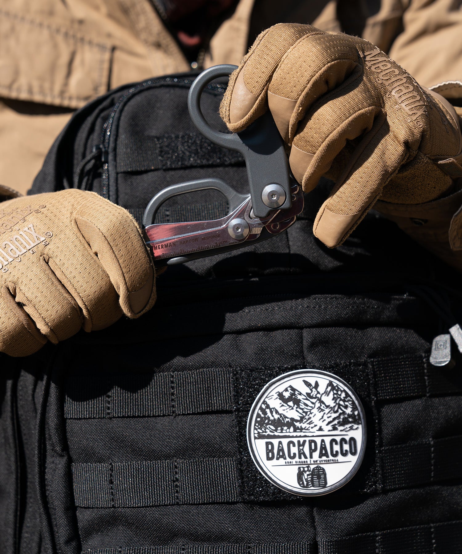 Paolo di backpacco apre le forbici Leatherman Raptor Response grige con i guanti mechanix