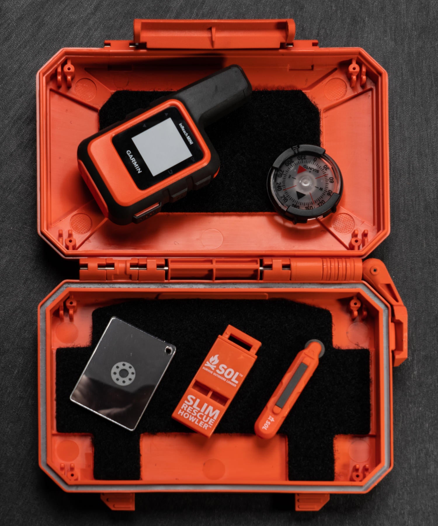 Thyrm DarkVault arancione usato come kit di emergenza con fischietto, acciarino, bussola e garmin in reach