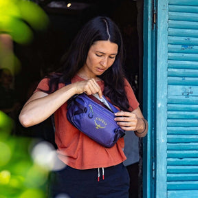 Osprey Transporter Waist Pack marsupio da 3 litri realizzato in tessuto tecnico con trama a griglia e logo frontale, dotato di tasca esterna con zip, cinghie di compressione laterali e cintura regolabile con fibbia a scatto per escursionismo e tempo libero.