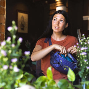 Osprey Transporter Waist Pack marsupio da 3 litri realizzato in tessuto tecnico con trama a griglia e logo frontale, dotato di tasca esterna con zip, cinghie di compressione laterali e cintura regolabile con fibbia a scatto per escursionismo e tempo libero.